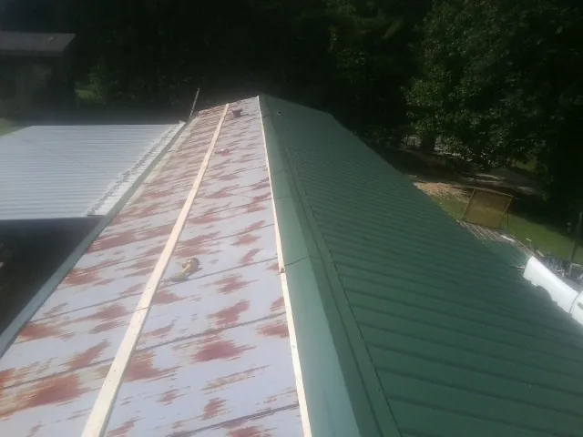 Old rusted panels beside newly installed green metal roofing — Wind Damage Roof Repair by Roofing Brothers in Hagerstown