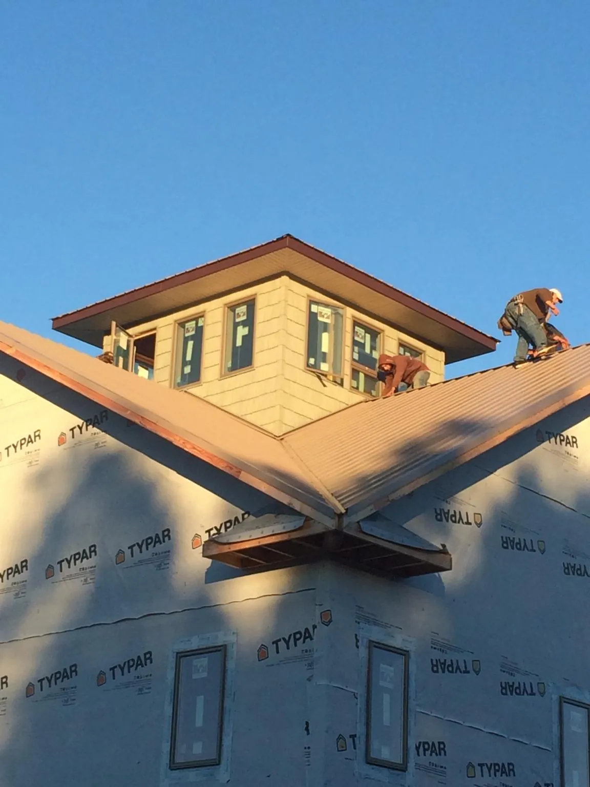 Roofers working around a rooftop cupola on a new metal roof at sunset — Roof Waterproofing in Hagerstown by Roofing Brothers